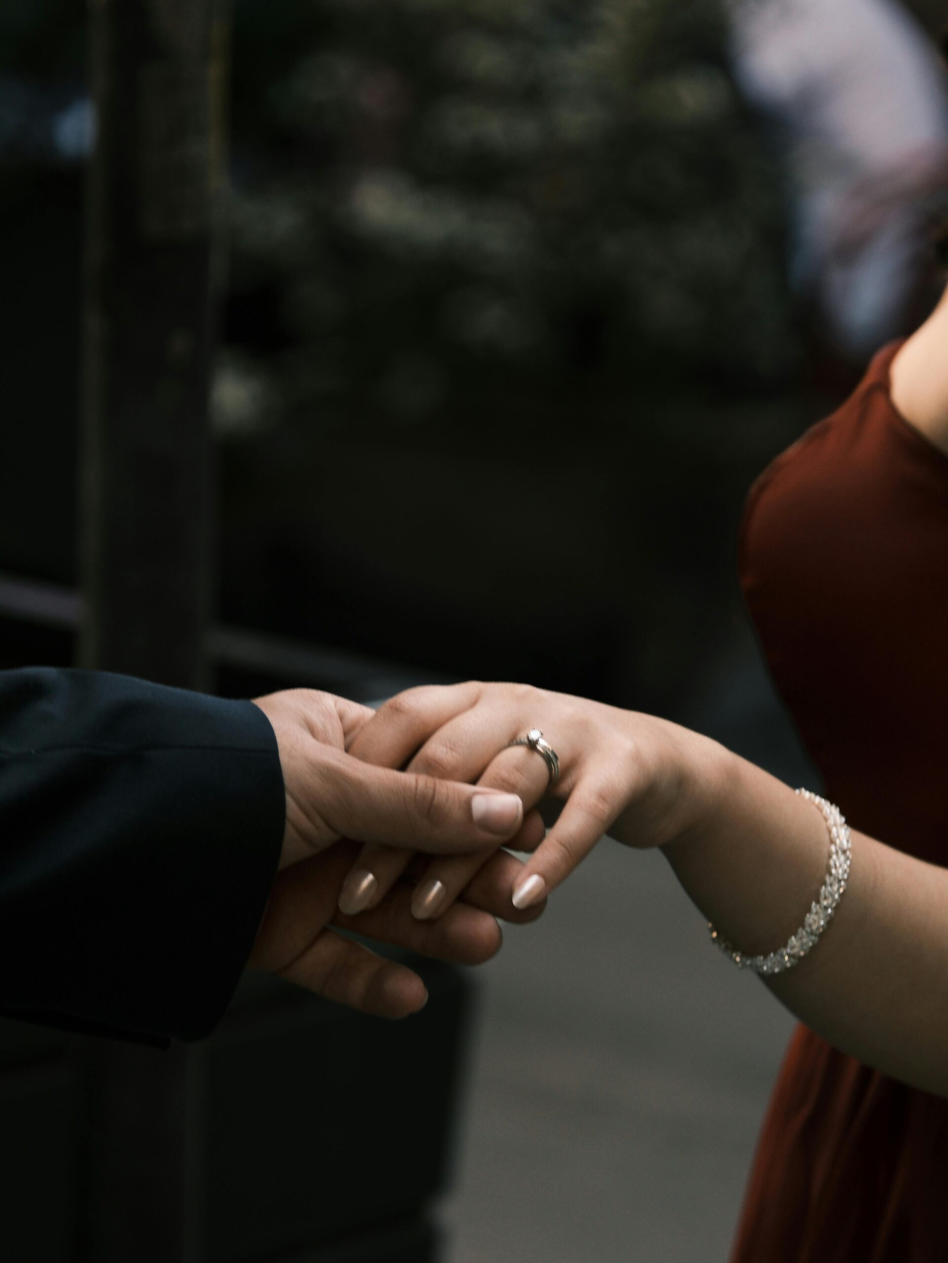 A close-up of a couple holding hands, displaying wedding rings and love.